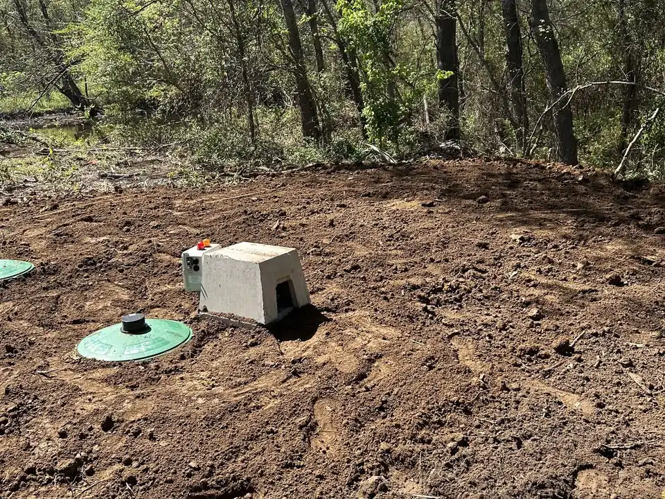 Aerobic system lid, control panel and concrete compressor cover in a wooded yard, aerobic septic system maintenance