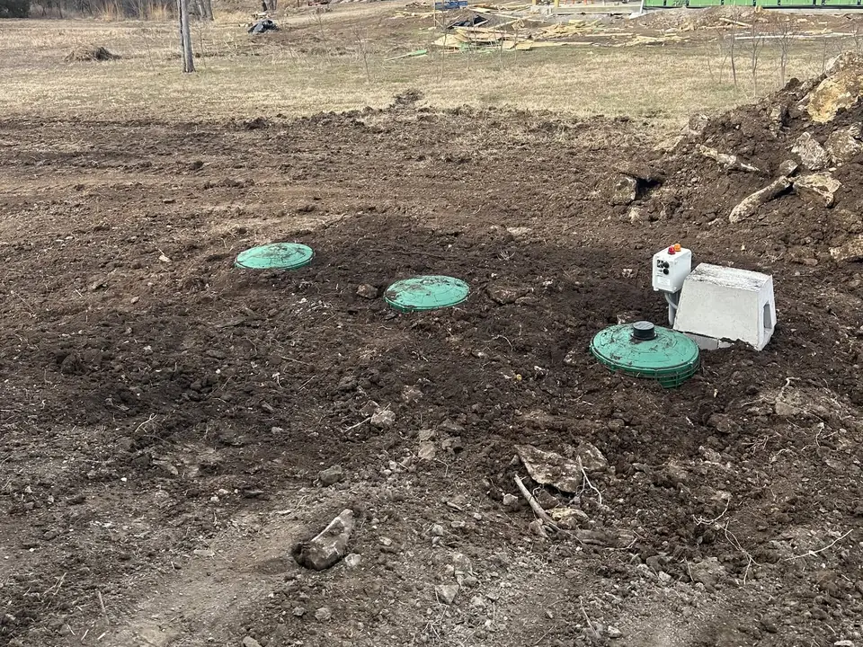 Aerobic system with green lids, a control panel and a concrete cover at a new home site, aerobic septic system maintenance