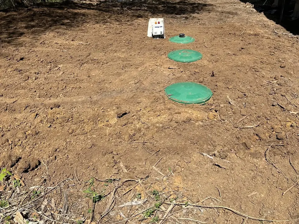 Finished aerobic system with three green lids and a control panel in fresh dirt, aerobic septic systems