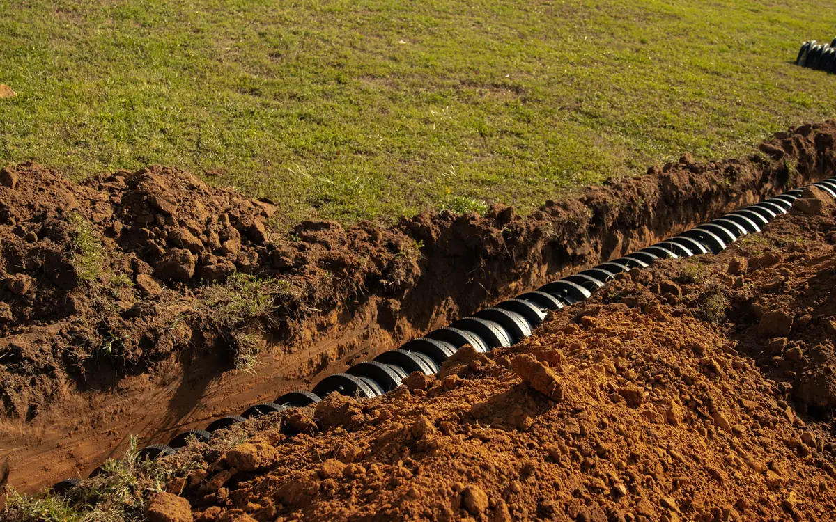 Row of lateral line chambers in an open trench across a lawn, lateral line repair