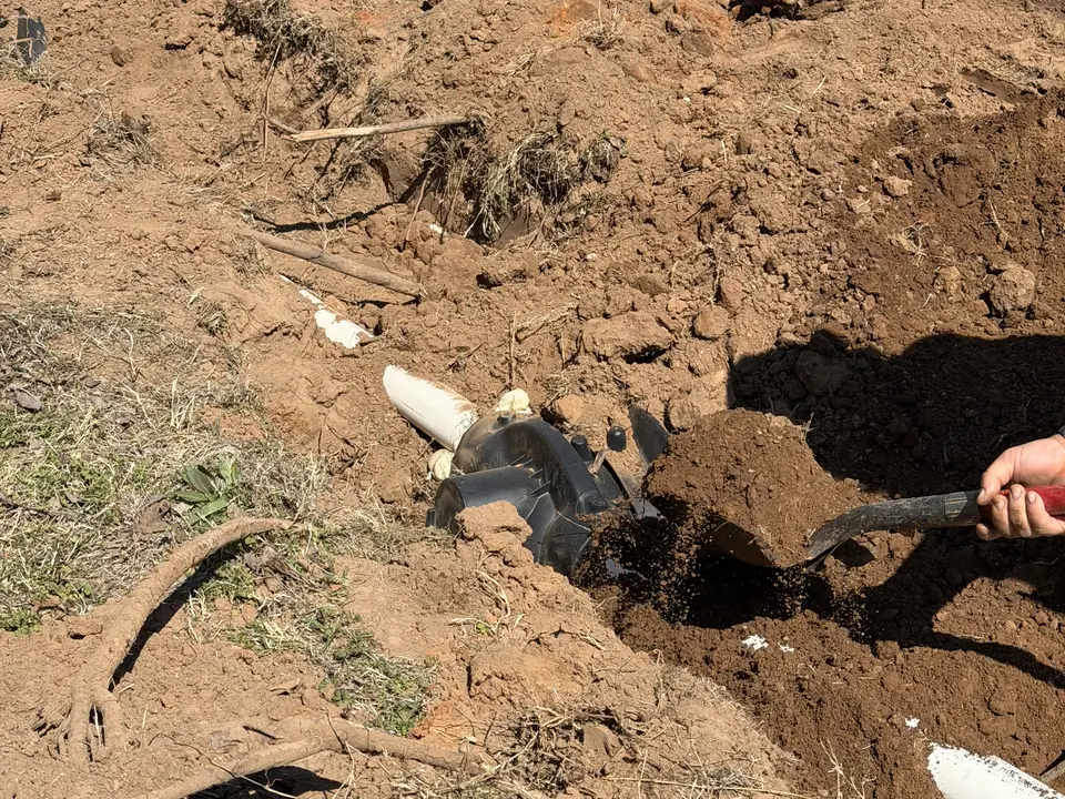 Shovel clearing dirt from an exposed septic line fitting, septic system repair